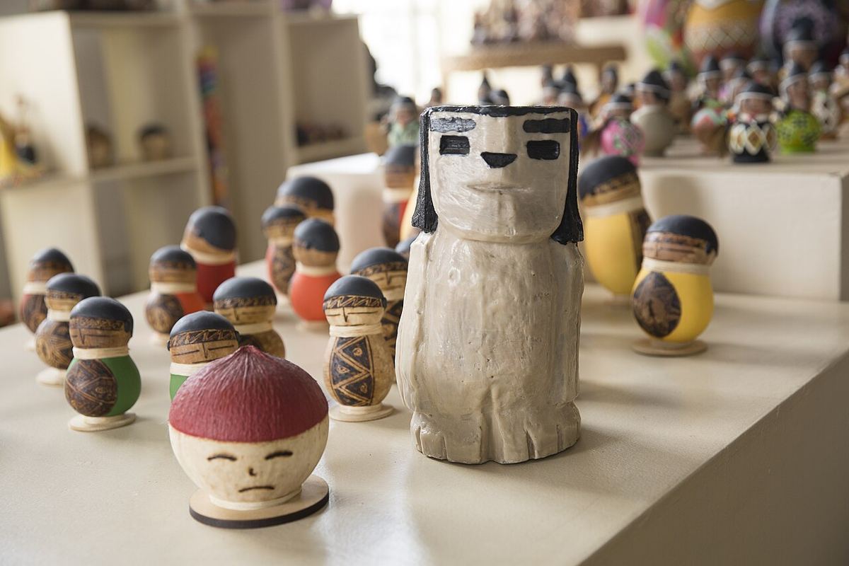 Bonecos de madeira e cabaça com cabelos pretos pintados, em uma loja de artesanato.